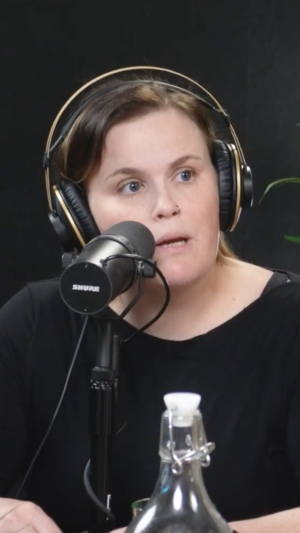 vertical image of trauma therapist and social worker Kristina Fifield. She's wearing headphones and speaking into a mic during recording of the podcast
