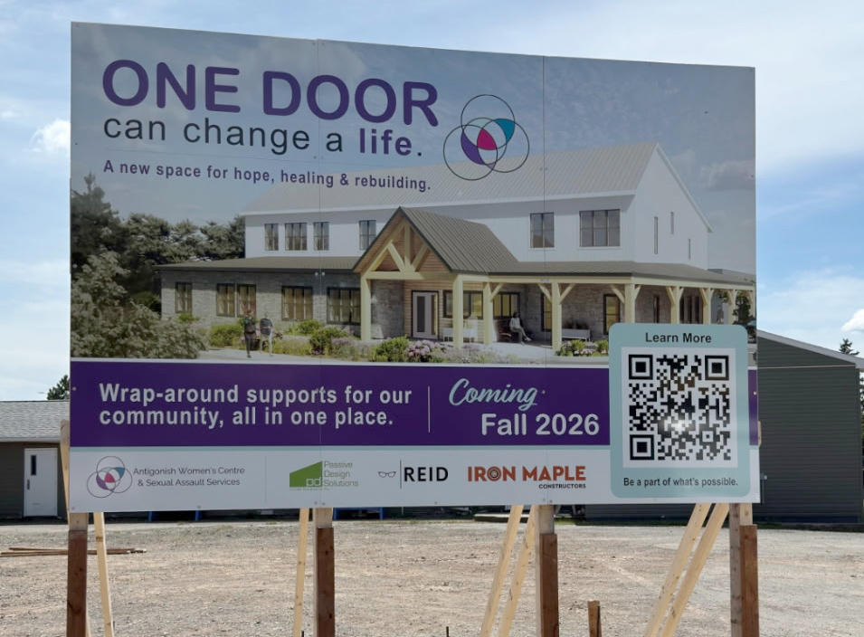 Photo of a billboard on an empty lot showing a rendering of the new Centre and sponsors, QR code, etc.