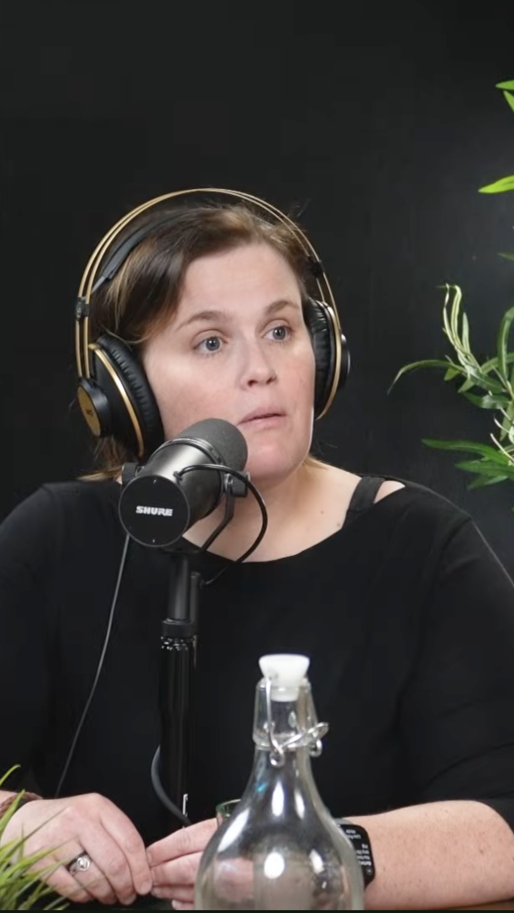 vertical image of trauma therapist and social worker Kristina Fifield. She's wearing headphones and speaking into a mic during recording of the podcast